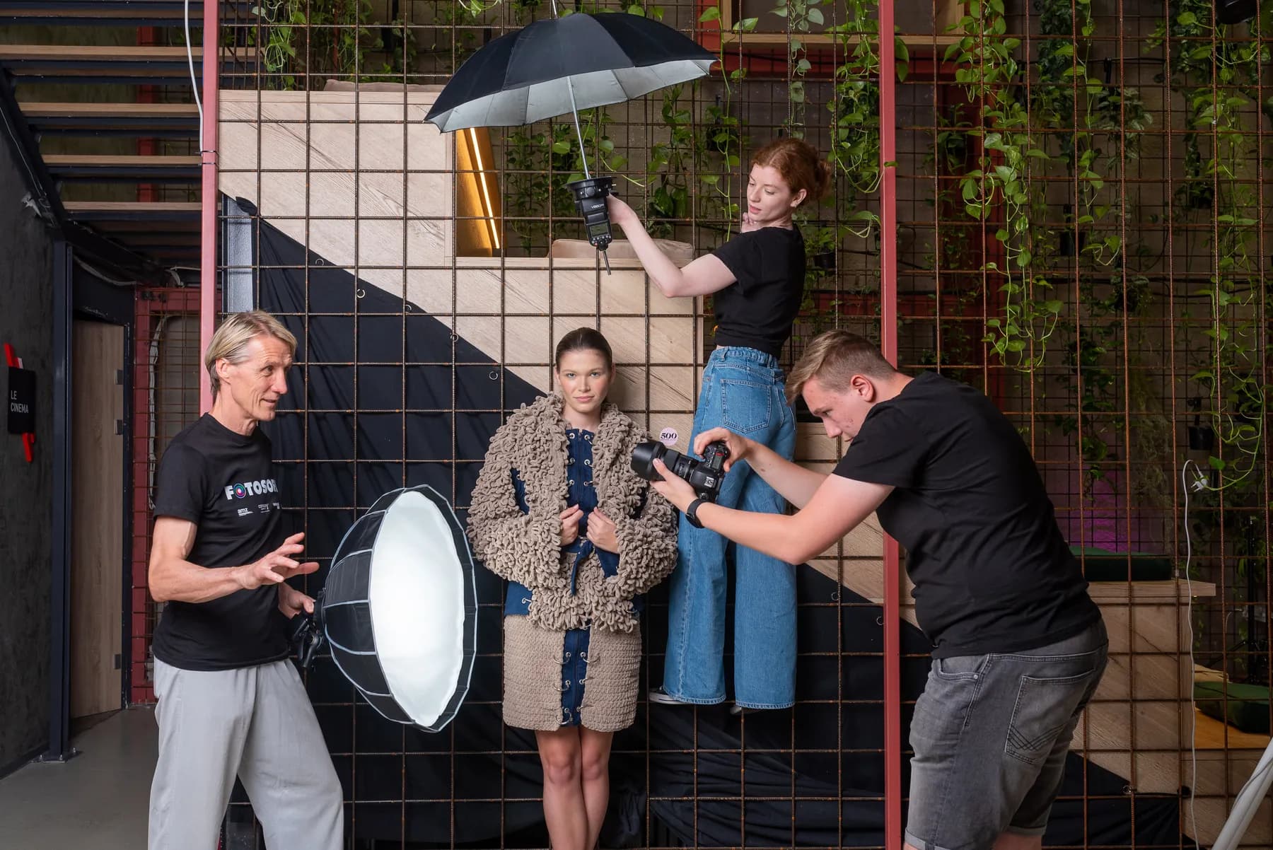 A fashion photo shoot at WESPA's creative space in Zagreb: a photographer, a lighting assistant with an umbrella flash and a softbox, and a model in front of a wall of climbing plants